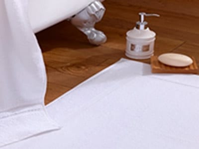 White towel, white bathmat, bar soap, and soap dispenser