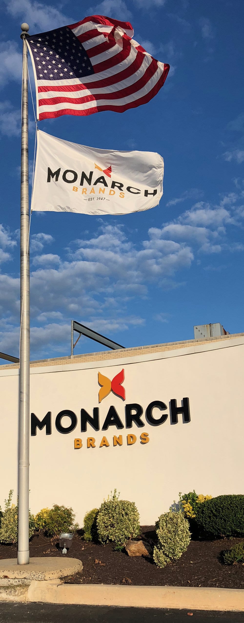 American and Monarch Brands Flag in front of Monarch Brands sign