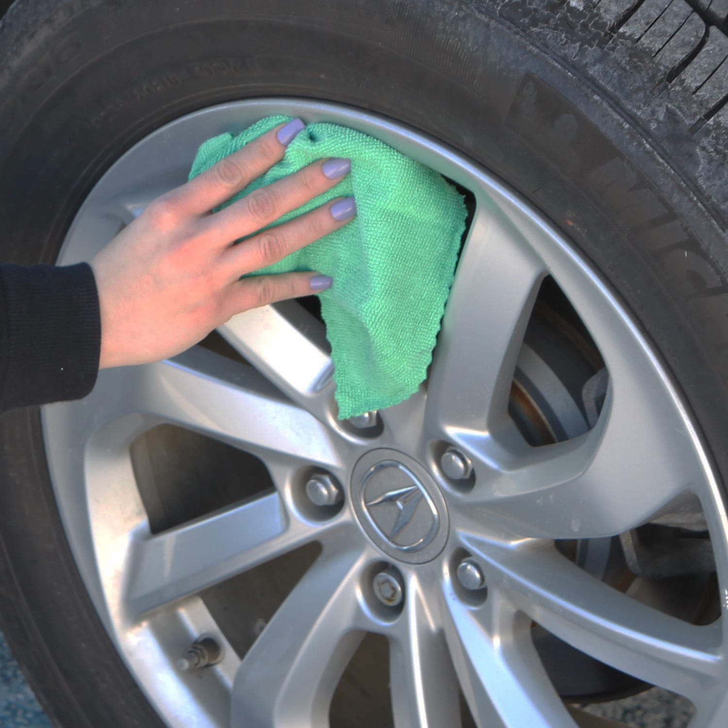 Woman cleaning wheel hubcap with Green SmartRags