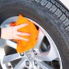 Woman using orange Huck Towel to wipe down wheel hubcap