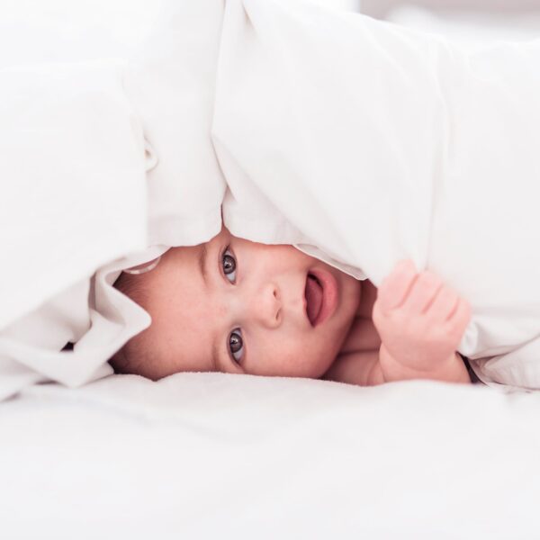 Baby under white linen comforter