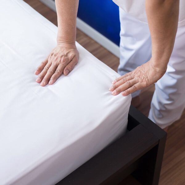 Housekeeping making white linen bed