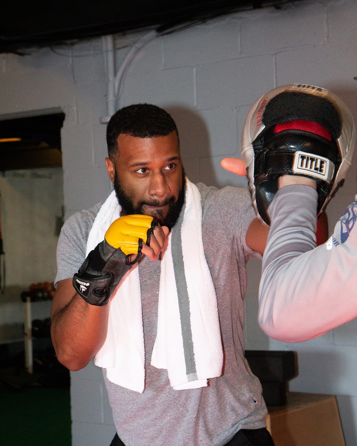 Man boxing with White Bath Towel with Grey Stripe around shoulder at gym