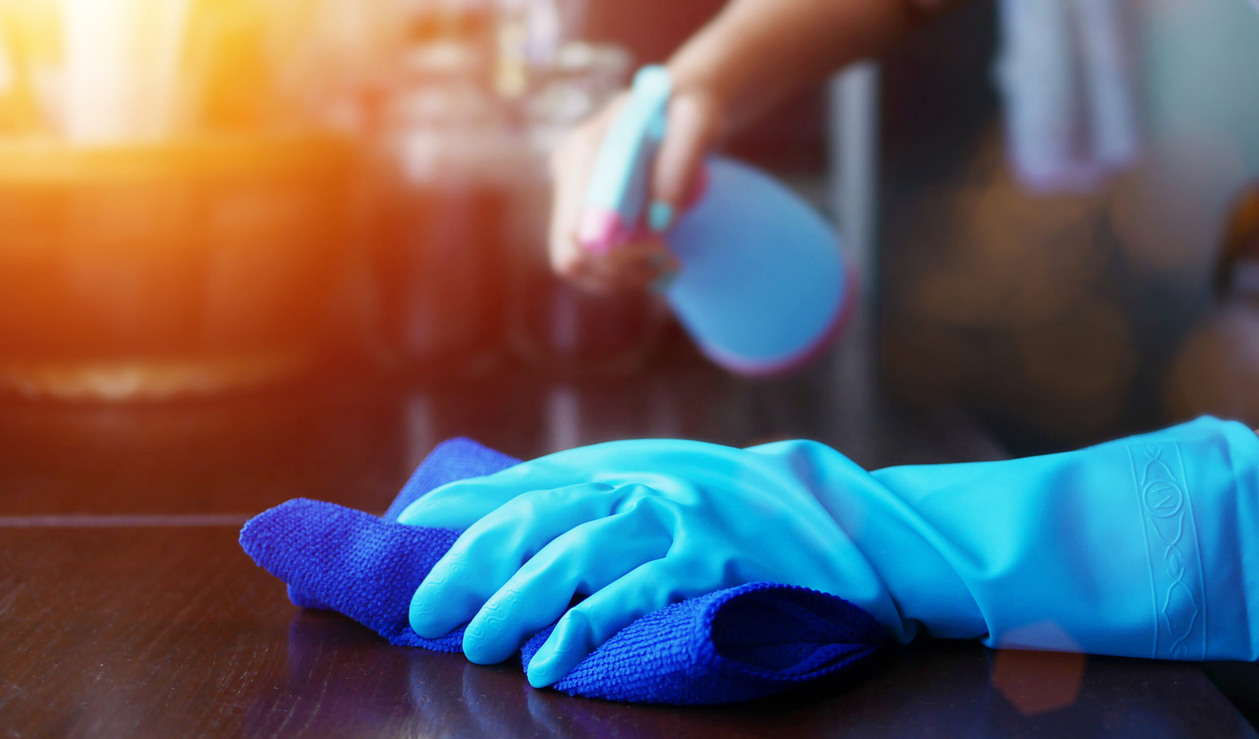 Person spraying and wiping down counter with Microfiber Cloth and gloves