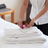 Hospitality placing flower on neatly folded towels in hotel room