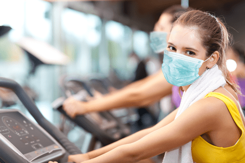 Girl wearing PPE mask on exercise bike