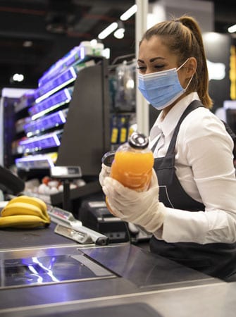 Cash register worker wearing PPE scanning items