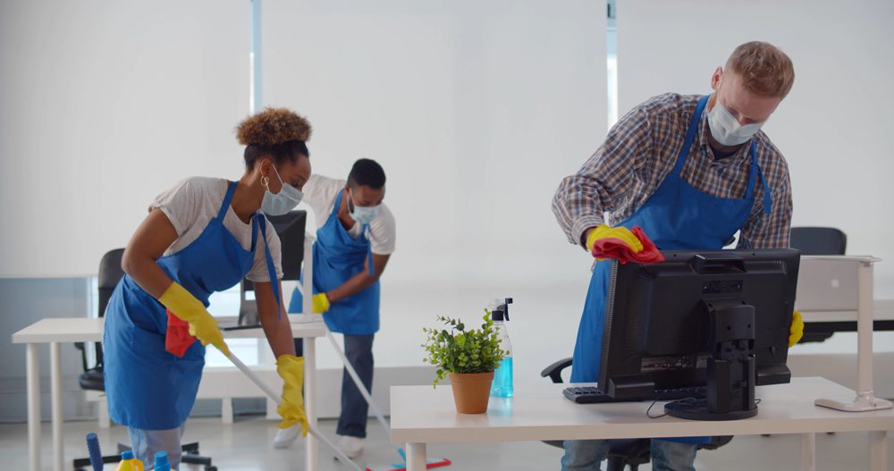 Group of people wearing PPE cleaning an office